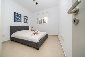 Ein Schlafzimmer mit Bett, Fenster, Tür und einer Lampe.