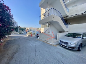 Ein Wohngebäude mit einem geparkten Auto, einer Treppe und blauem Himmel.