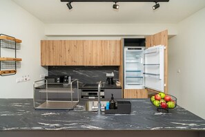 A modern kitchen with wooden cabinets, a black countertop, a built-in oven, and a refrigerator.