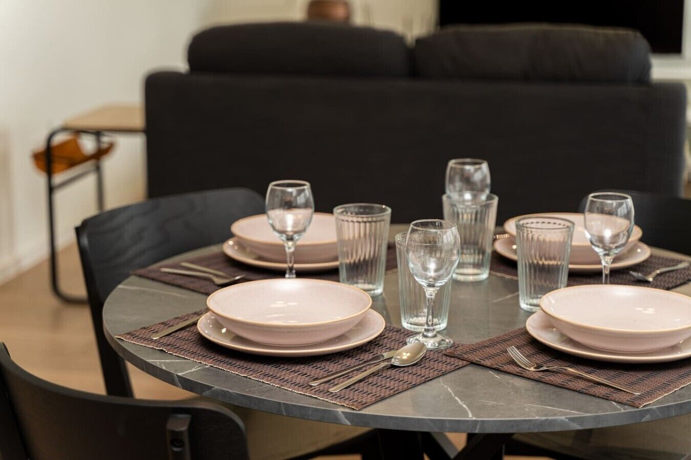 Una mesa de comedor dispuesta con platos, vasos y cubiertos.