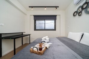 Quarto com cama, escrivaninha, janela e ar-condicionado fixado na parede.