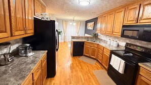 A kitchen with wooden cabinets, a black refrigerator, a microwave, and a stove. - Near ATL & Stone Mountain/ Sleeps 12/  King Suite (Loganville)