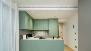 A modern kitchen with teal cabinetry, a central island, and a microwave. - Amazing new 2 bedroom flat near casino beach mall (Limassol)