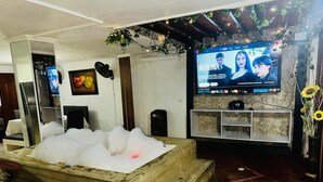 A room with a wooden bench, a television, and a wall-mounted shelf with decorative items. - Cozy apartment in Itagüí | Wi-Fi | 2 bathrooms | Near Medellín (Itagüí)
