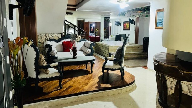 A living room with a sofa, armchair, and coffee table. There is a staircase leading to another room. - Cozy apartment in Itagüí | Wi-Fi | 2 bathrooms | Near Medellín (Itagüí)