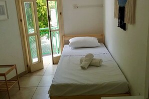 A single bed with white linens, a wooden headboard, and a pair of rolled towels on the bed. - Private room in a shared flat (Nicosia)