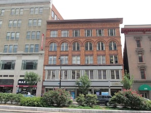 A multi-story building with a mix of brick and stone facades, featuring storefronts on the ground floor. - Trumbull Apartments  (Hartford)