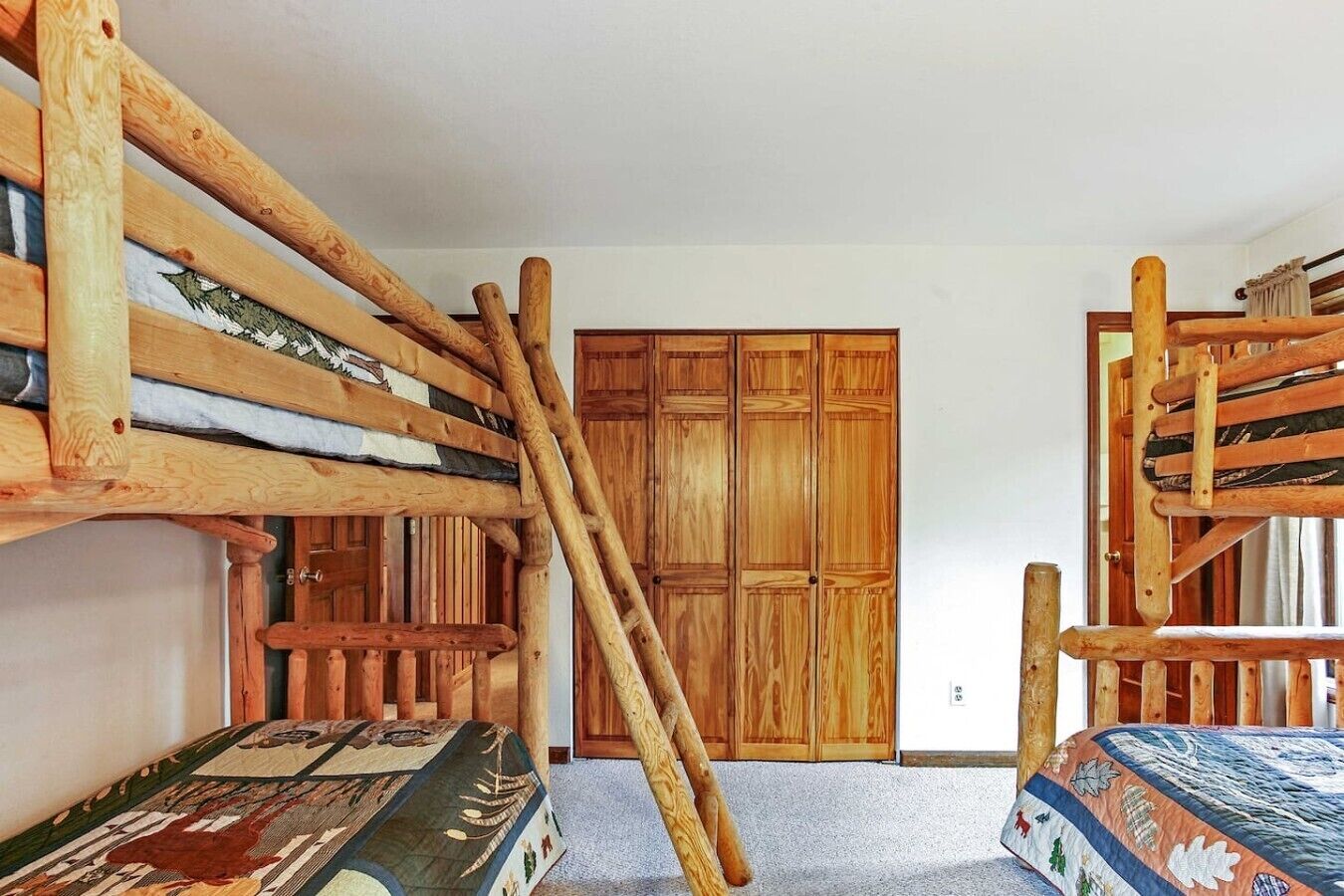 A room with bunk beds, wooden wardrobe, and a carpeted floor.