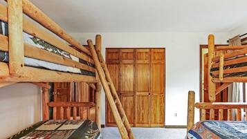 A room with bunk beds, wooden wardrobe, and a carpeted floor.