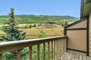 Un balcon donnant sur un paysage verdoyant et une colline lointaine.