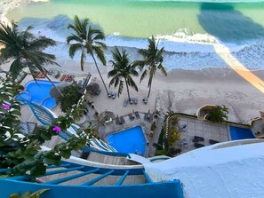 Ein Strandresort mit Pool, Palmen und einer Treppe, die zum Strand führt.
