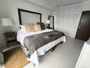 Ein Schlafzimmer mit einem großen Bett, zwei Nachttischen, einem Schrank und einer Tür.