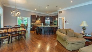 A spacious living area with a dining table, a sofa, and a kitchen with dark wooden cabinets and a central island. - Duffers Delight at Rumbling Bald (Lake Lure)