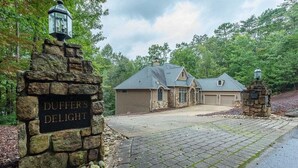 A house with a stone entrance, a garage, and a paved driveway. - Duffers Delight at Rumbling Bald (Lake Lure)