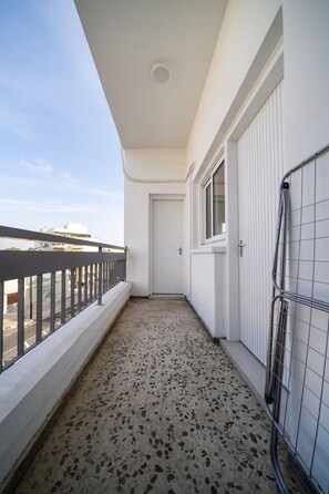 Un balcó estret amb sòl de rajola, barana metàl ·lica i una porta que dona a l'interior.