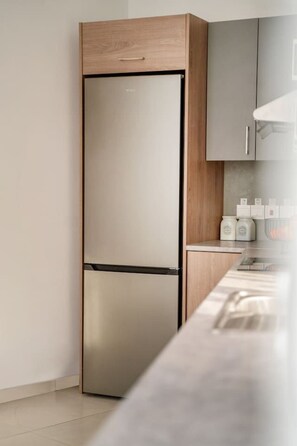 Una cocina con un refrigerador de acero inoxidable, armarios de madera y una encimera con frascos.
