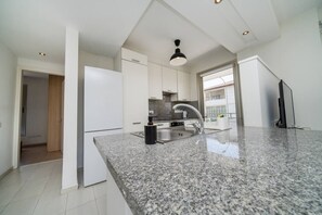 A modern kitchen with granite countertops, stainless steel appliances, and a large window providing natural light.