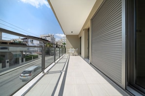 A balcony with a view of a street, a car, and buildings.