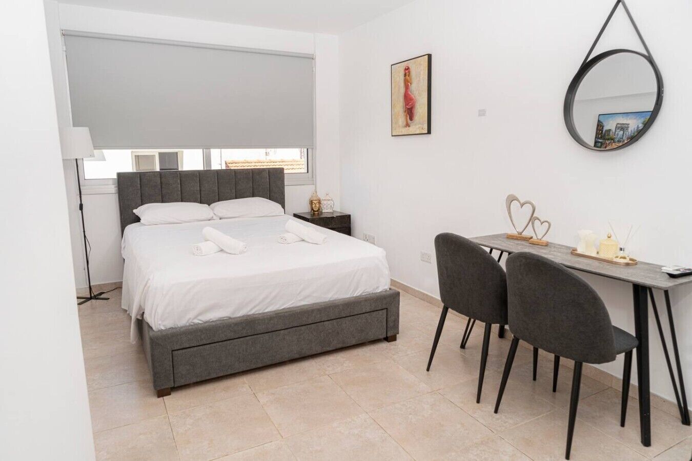 Een moderne slaapkamer met een bed, nachtkastje, bureau en stoelen.