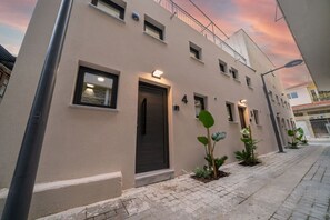 A modern building with a flat facade, numbered 4, featuring a dark entrance door, small windows, and a balcony. - New luxury studio in historic center (Limassol)