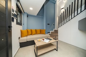 A modern living room with a sofa, coffee table, and a staircase. - New luxury studio in historic center (Limassol)