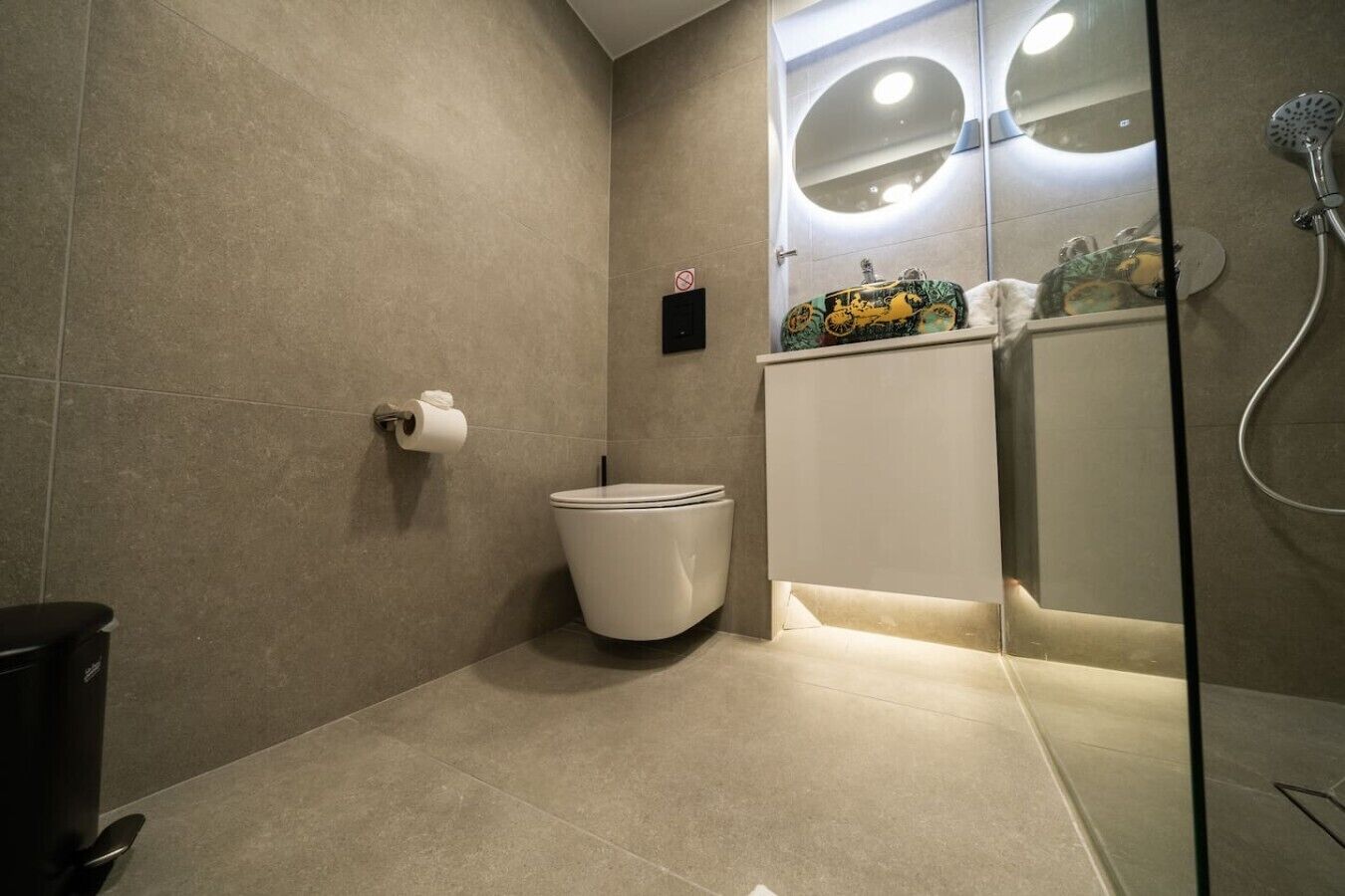 Un baño moderno con inodoro, ducha y espejo con luces.
