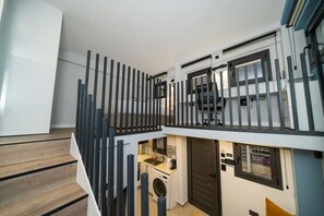A modern apartment with a kitchen, a washing machine, and a balcony with a railing. - New luxury studio in historic center (Limassol)