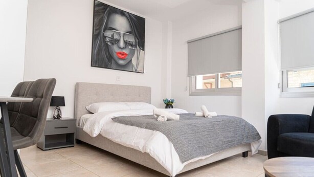 Ein modernes Schlafzimmer mit einem Bett, einem Schreibtisch, einem Stuhl und einem großen Fenster.