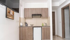 Eine kleine Küche mit Holzausstattung, einem integrierten Geschirrspüler und einer gefliesten Spritzschutzwand.
