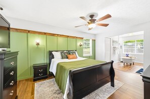 Ein Schlafzimmer mit einem Bett, Nachttischen, einem Deckenventilator und Blick ins Freie.