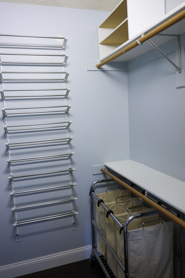 A storage area with metal racks, a white shelf, and a cart with bags.