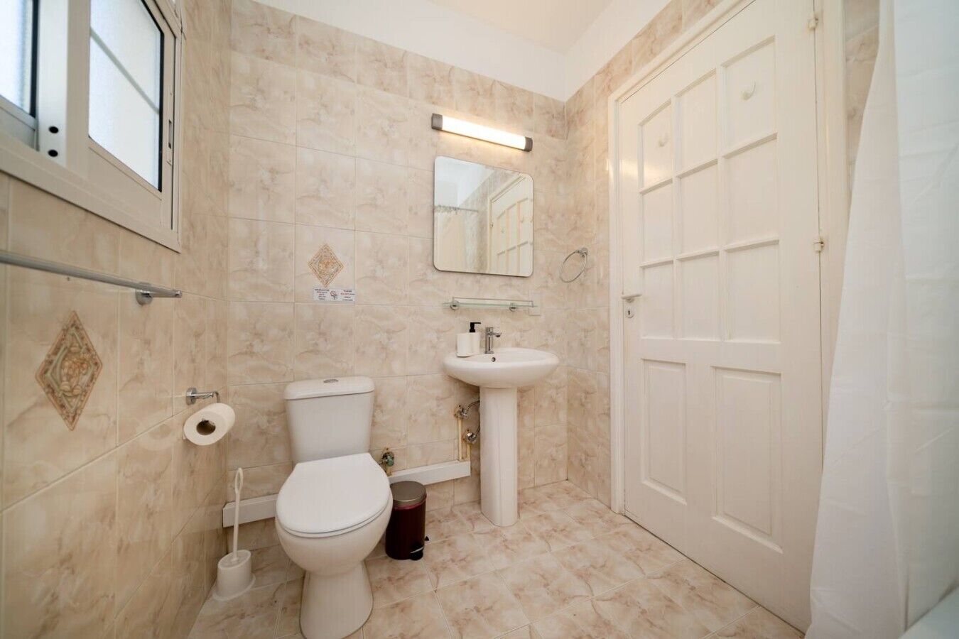 A bathroom with a toilet, sink, and mirror.
