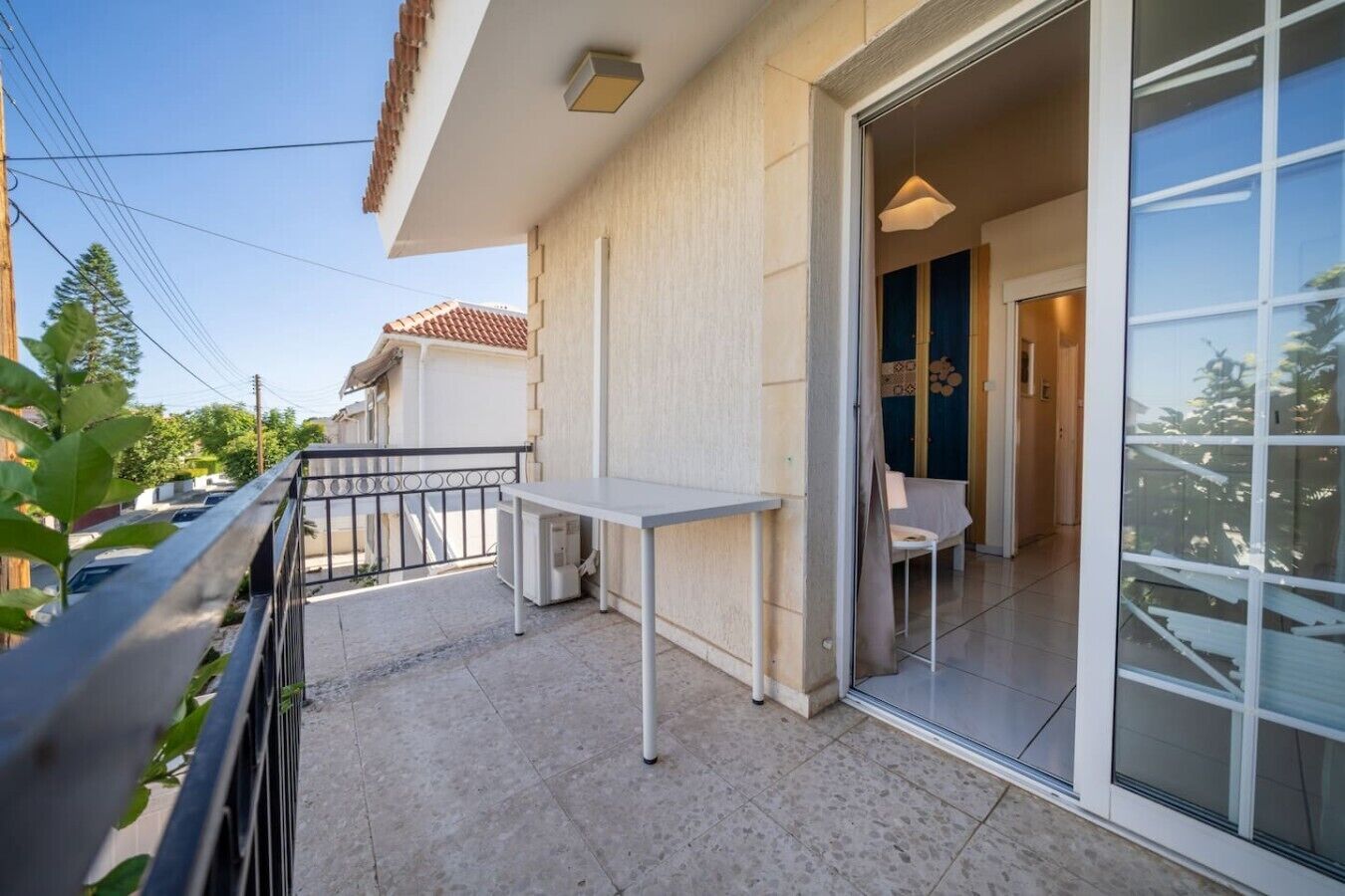 A balcony with a table and chairs, a sliding glass door, and a view of neighboring buildings.