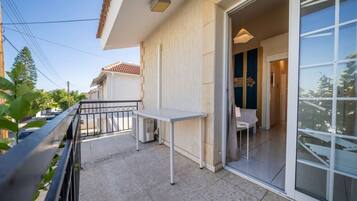 A balcony with a table and chairs, a sliding glass door, and a view of neighboring buildings.