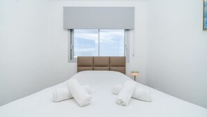 Een moderne hotelkamer met een groot bed, een hoofdbord, een raam en een bedlamp.