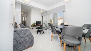 Een moderne woonkamer met een bank, eettafel, stoelen en een televisie.