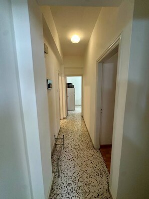A narrow hallway with white walls, a speckled floor, and a ceiling light. - 2 bedroom flat by the sea (Larnaca)