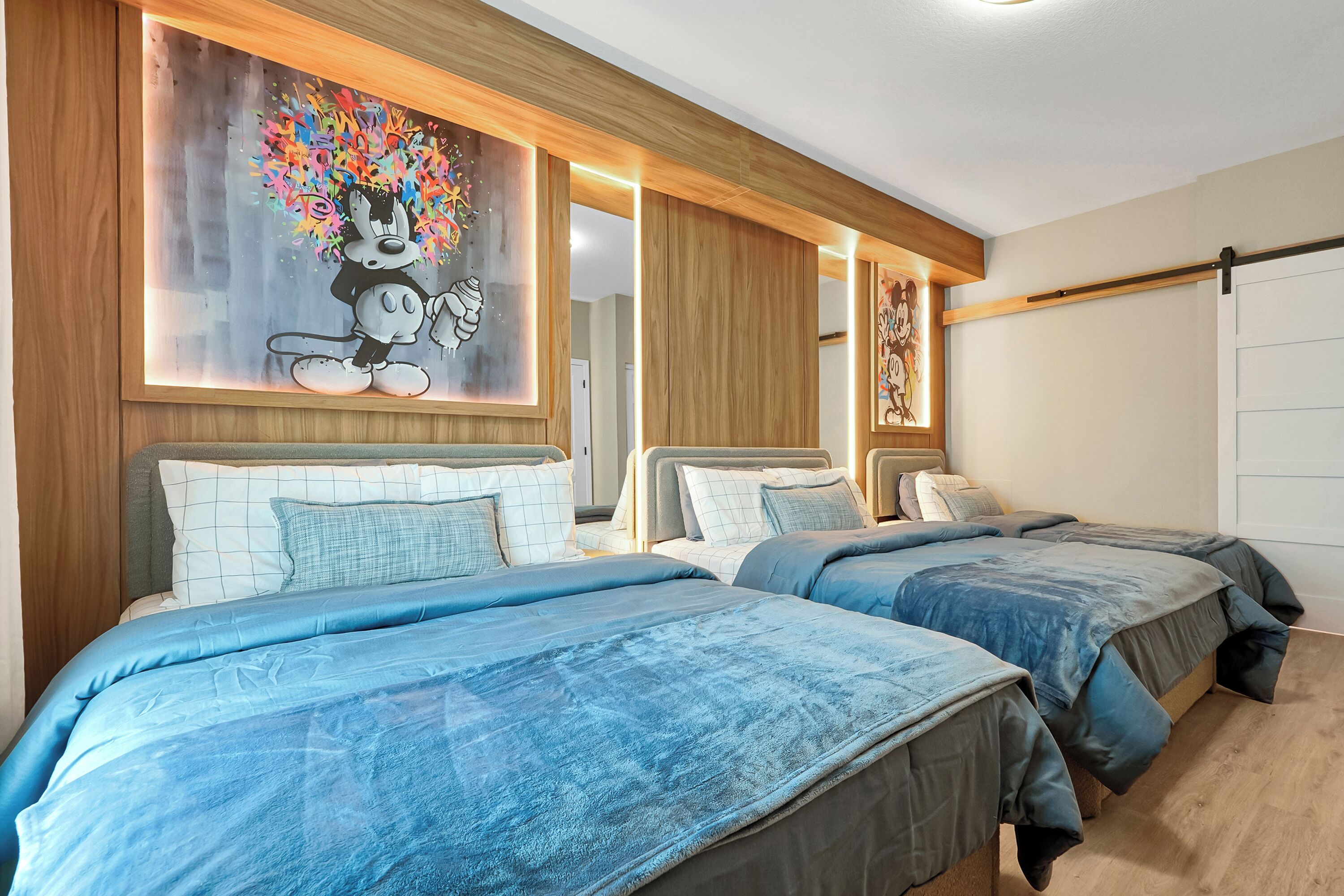 A hotel room with two beds, a large wall mural, and a sliding door.