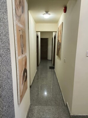 A hallway with a tiled floor, light-colored walls, and a ceiling light fixture. - Modern studio in historic center near beach (Limassol)
