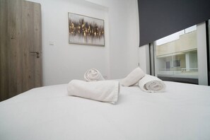 A modern hotel room with a bed, a painting, and a window.