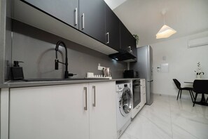 A modern kitchen with a built-in washer and dryer, a stainless steel sink, and a dining area with a table and chairs.