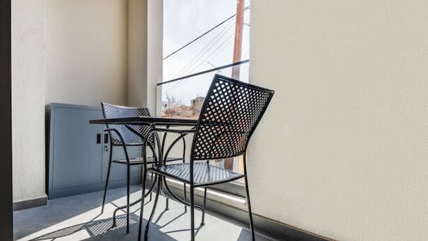 A balcony with a table and chairs, a view of the sky, and a building in the background. - New deluxe studio in the heart of Limassol (Limassol)