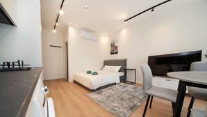 A compact hotel room with a bed, a dining table, a TV, and a kitchenette. - New deluxe studio in the heart of Limassol (Limassol)