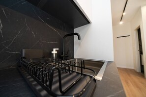 Una cocina moderna con un salpicadero de mármol negro, un lavamanos de acero inoxidable y un perchero negro.