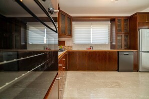 A modern kitchen with wooden cabinets, a stainless steel refrigerator, and a dishwasher. - 3 bedroom flat central, beach, walking streets (Limassol)