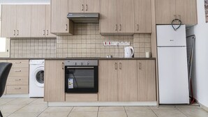Una cocina moderna con armarios de madera clara, horno empotrado, lavadora y refrigerador.