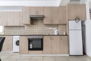 A modern kitchen with light wood cabinets, a built-in oven, a washing machine, and a refrigerator. - Private room in shared flat (Nicosia)