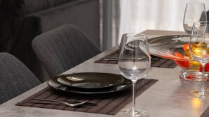 A dining table set with plates, cutlery, and glasses, with a sofa and curtains in the background. - 3 bedroom flat near center (Nicosia)