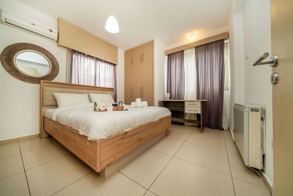 A bedroom with a wooden bed, a desk, a wardrobe, and a radiator.