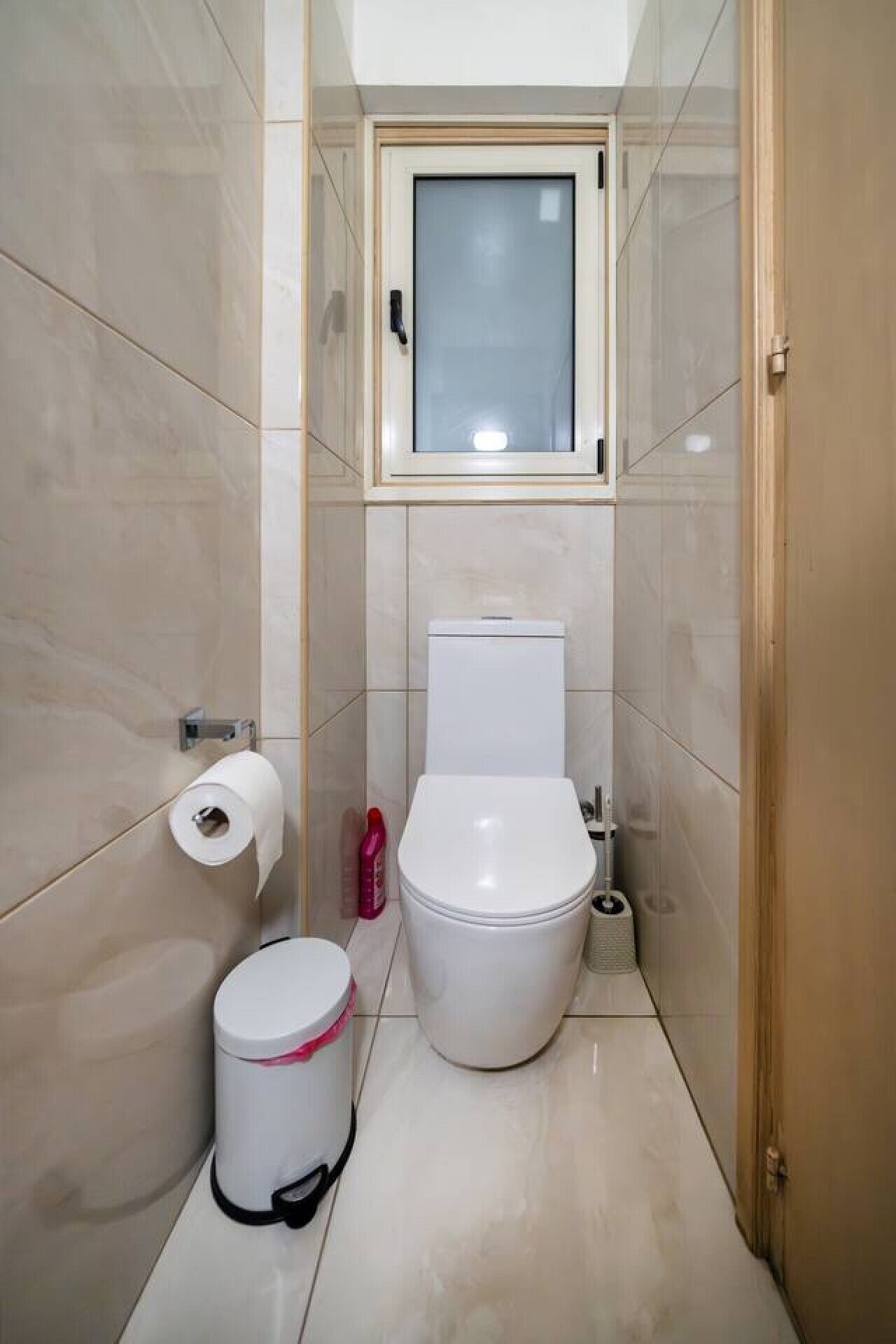 Ein kleines, modernes Badezimmer mit Toilette, Bidet und einem Fenster über der Toilette.